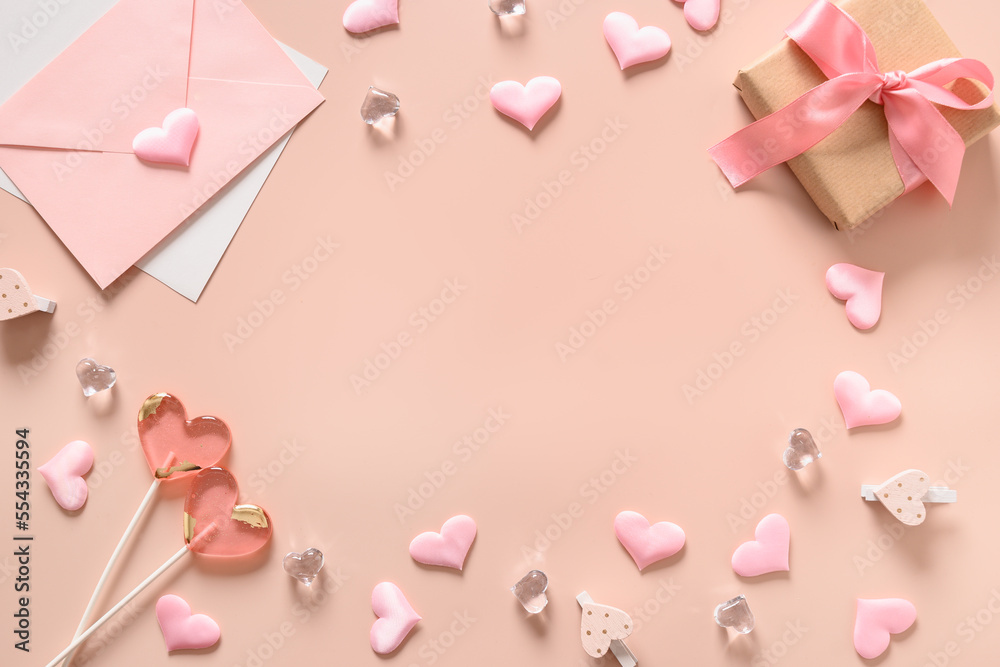 Valentine's day frame with pink lollipops, pink envelope, gift and sweets as heart on pink background. View from above. Copy space.