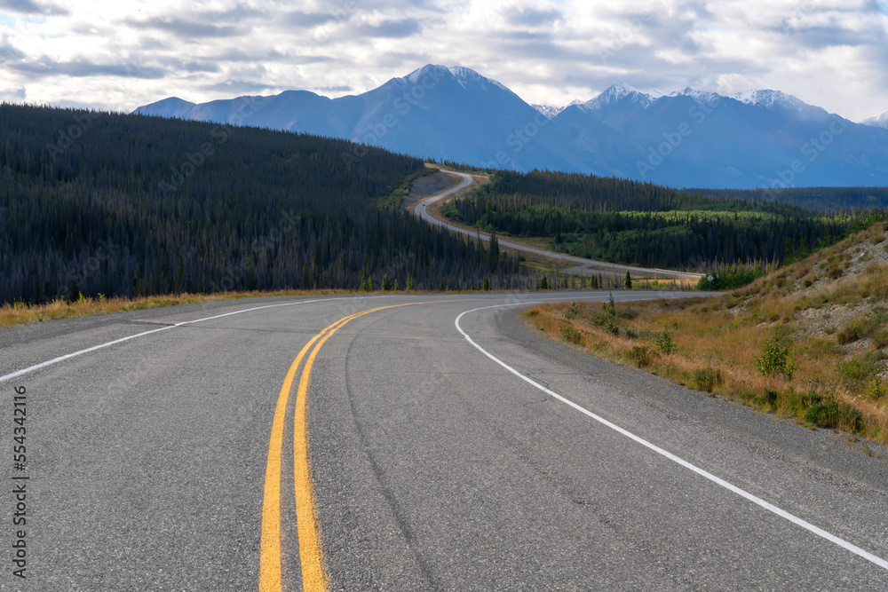 The Alaska Highway winding its way north on its way to Alaska with the mountains of Kluane National Park seen in the distance; Yukon, Canada The Alaska Highway winding its way north on its way to Alaska with the mountains of Kluane National Park seen in the distance; Yukon, Canada