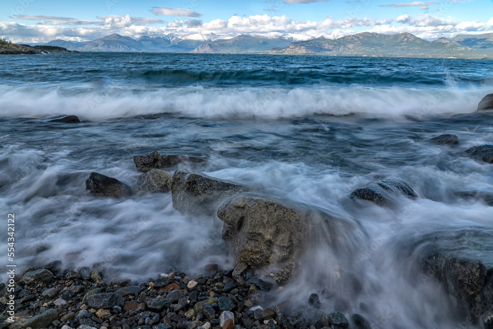 Waves crash into the rocky shore of Kluane Lake on a windy day. Klaune Lake is the largest lake in the Yukon; Yukon, Canada Waves crash into the rocky shore of Kluane Lake on a windy day. Klaune Lake is the largest lake in the Yukon; Yukon, Canada