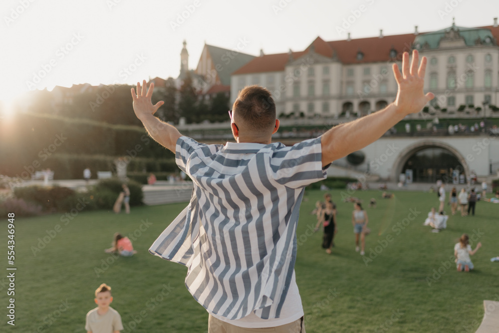 A photo from the back of the man with outstretched hands in the royal garden