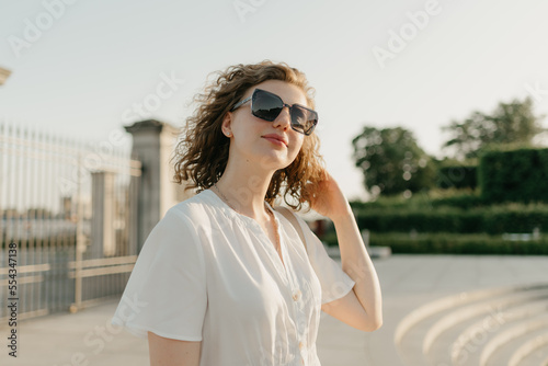 Obraz na płótnie A woman with curly hair in sunglasses is posing in the park w salonie