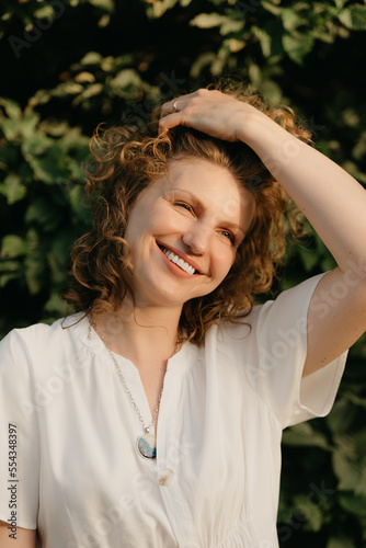Obraz na płótnie A woman with curly hair is posing in the park at the sunset. w salonie