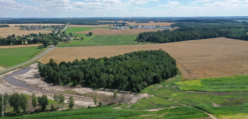 Aerial photography of the flat terrain of the Brest region in Belarus in the summer. Belarusian agriculture in the summer from a height. Fields with wheat harvest. Green forests of Belarus.
