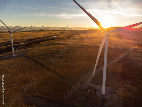 Aerial windmills at sunset with sun rays producing sustainable energy on the Alberta prairies in Canada.