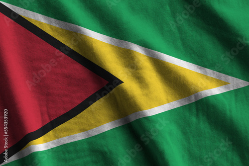 Guyana flag with big folds waving close up under the studio light indoors. The official symbols and colors in fabric banner photo