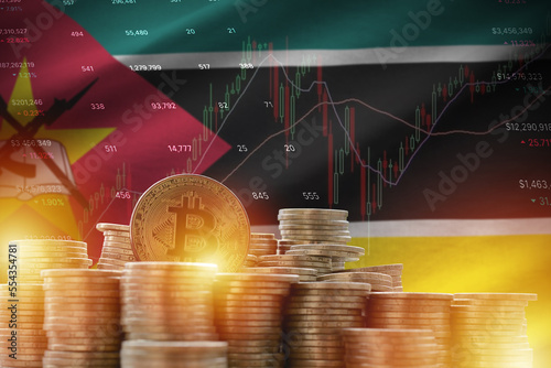 Mozambique flag and big amount of golden bitcoin coins and trading platform chart. Crypto currency concept photo