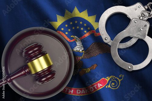 North Dakota US state flag with judge mallet and handcuffs in dark room. Concept of criminal and punishment, background for guilty topics photo