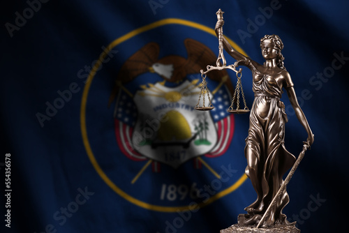Utah US state flag with statue of lady justice and judicial scales in dark room. Concept of judgement and punishment, background for jury topics photo