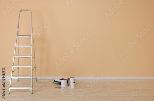 Metal stepladder near pale orange wall indoors, space for text. Room renovation photo