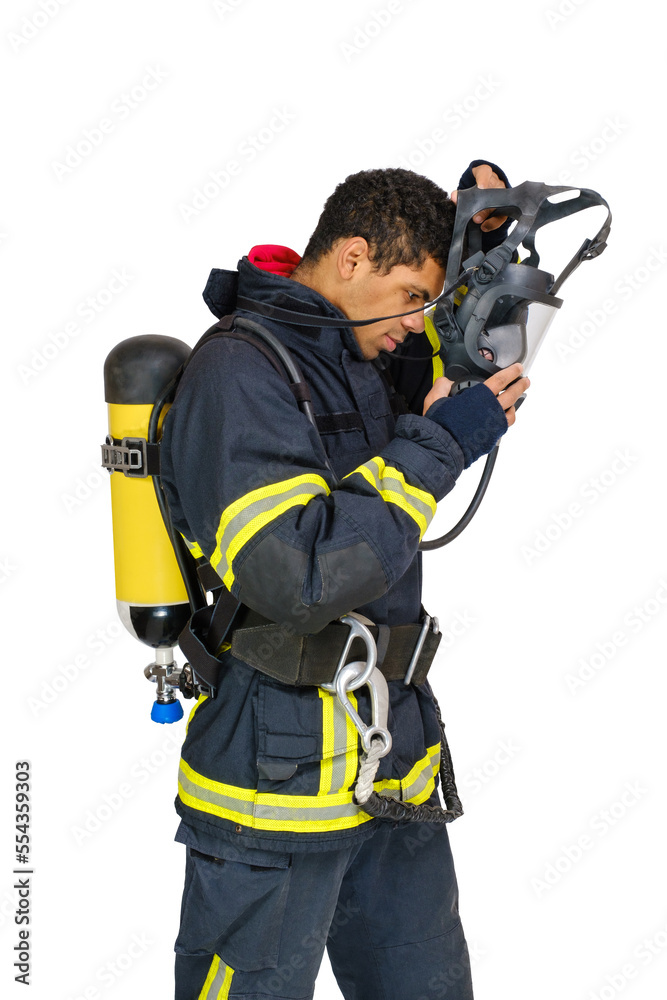 Young smiling African-American fireman in uniform and with air breathing apparatus takes off protective mask from his head. Side view, isolated on white background Young smiling African-American fireman in uniform and with air breathing apparatus takes off protective mask from his head. Side view, isolated on white background