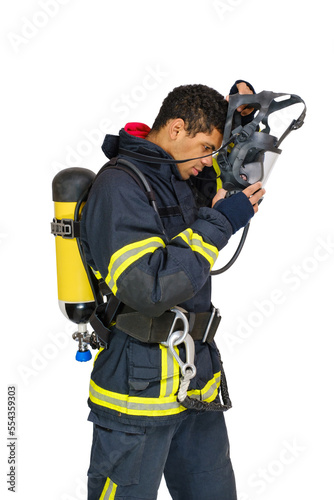 Young smiling African-American fireman in uniform and with air breathing apparatus takes off protective mask from his head. Side view, isolated on white background