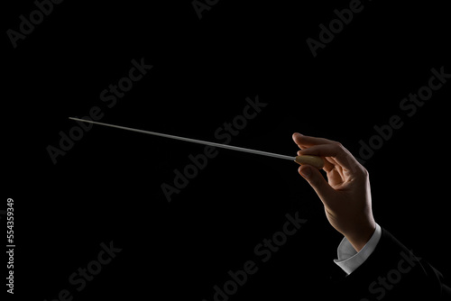 Professional conductor with baton on black background, closeup