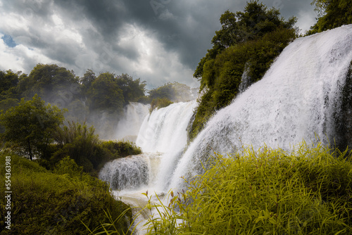 Fototapeta Naklejka Na Ścianę i Meble -  Detian transnational waterfall, in a misty weather. It is the largest waterfall in Asia, spanning China and Vietnam. Dramatic sky, copy space for text