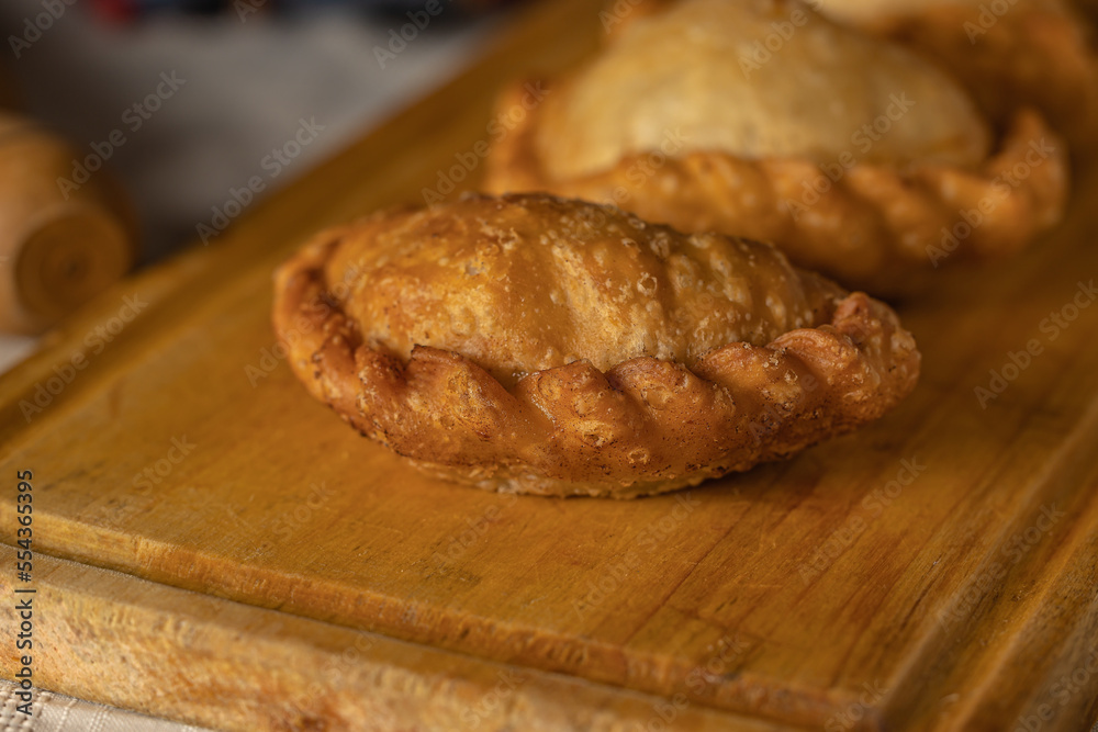 Close up of fried Argentine empanadas on a wooden board.
