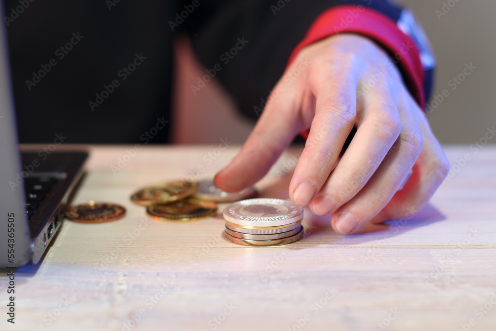 calculation of a pile of coins on a table next to a laptop by a person calculation of a pile of coins on a table next to a laptop by a person