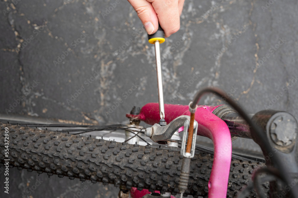 A close-up of male hand that uses screwdriver tool to adjust and repair the bicycle crank assembly