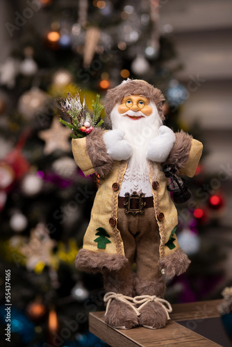 a very cute santa claus toy in front of the christmas tree