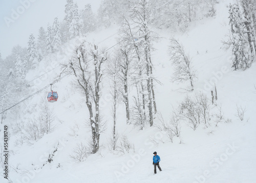 Man go downhill skiing in a mountain forest in snowstorm in winter