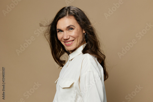 a beautiful horizontal portrait of an adult woman with black hair flowing in the wind standing in a white shirt. Studio photo with an empty space on the background