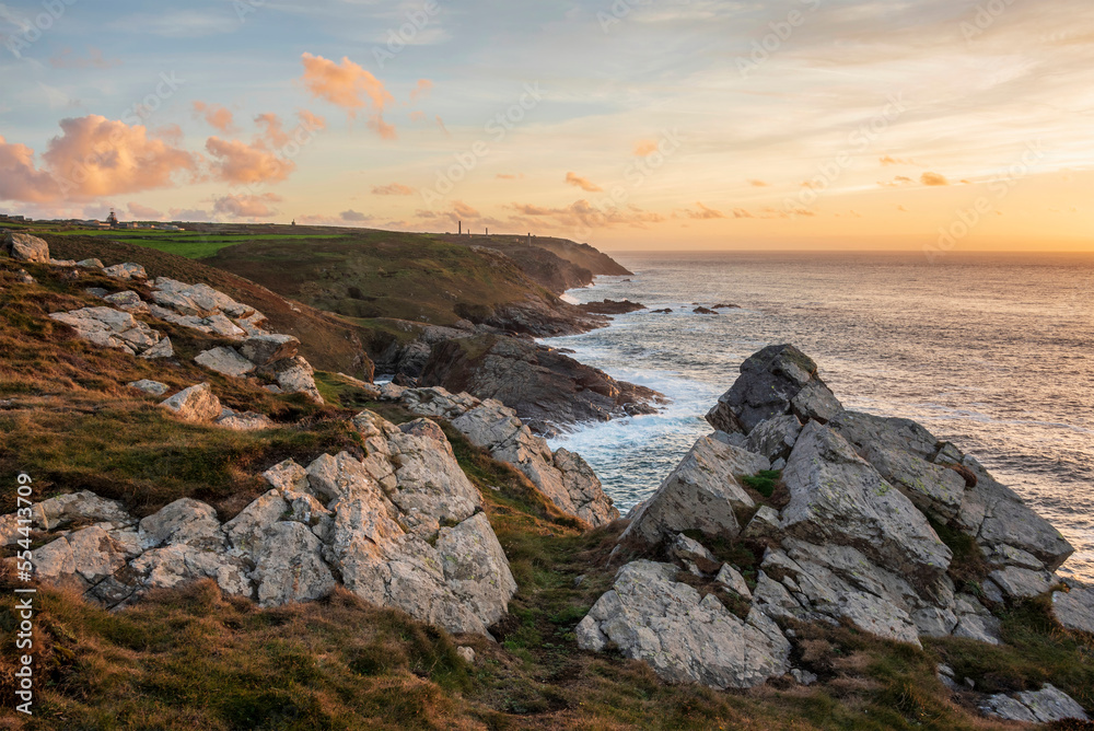 Stunning sunset landscape image of Cornwall cliff coastline with tin mines in background viewed from Pendeen Lighthouse headland