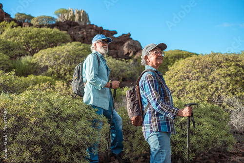 Smiling old senior couple enjoying outdoor excursion in mountain environment. Beautiful active elderly people having healthy lifestyle in retirement