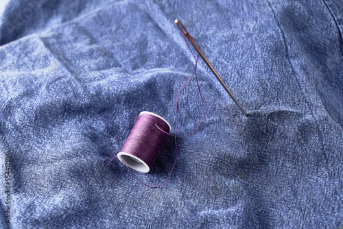 needles and thread on the background of torn jeans the concept of reasonable consumption of needlework for small businesses