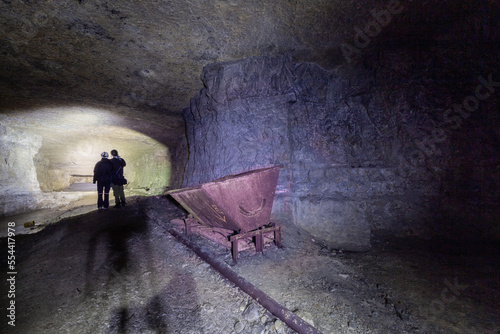 Old mine, deep underground, with an old lorry on rails. Siloette of a couple. photo