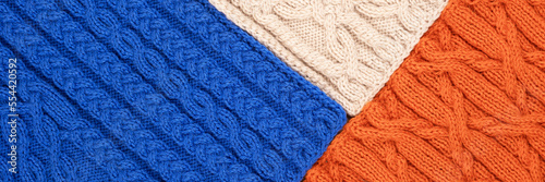 Knitted blue orange and beige background. Large knitted fabric with a pattern. Close-up of a knitted blanket. Banner