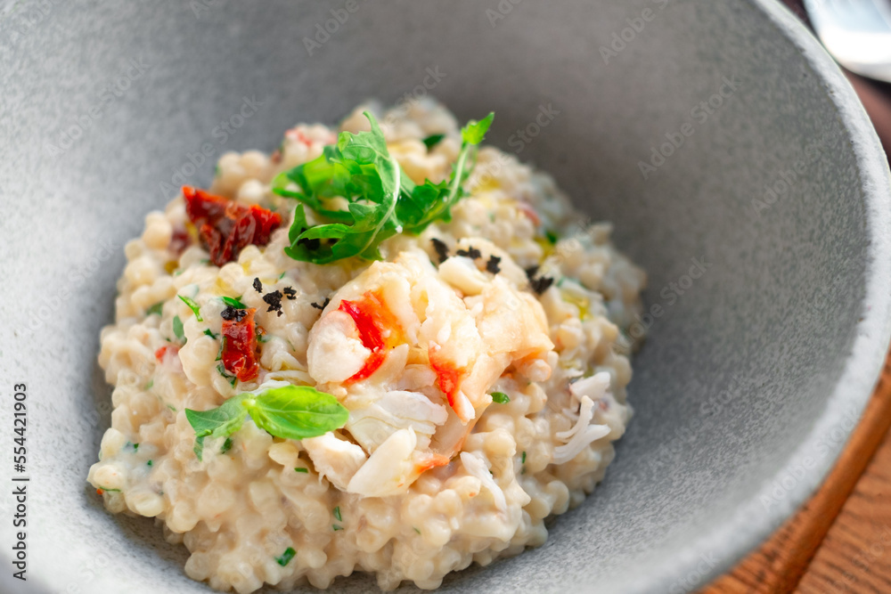 Risotto with crab meat and vegetables is served in a bowl. Dish with rice and seafood close up Risotto with crab meat and vegetables is served in a bowl. Dish with rice and seafood close up