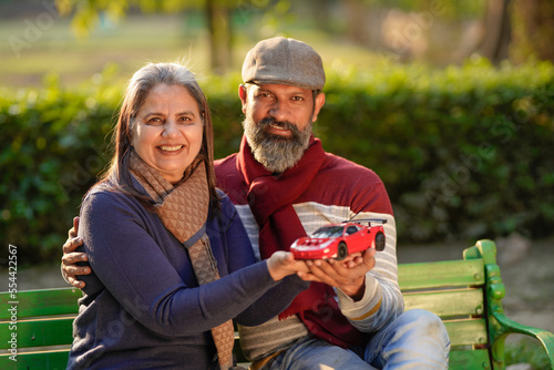 Indian old couple holding car toy in hand at park. car loan concept.