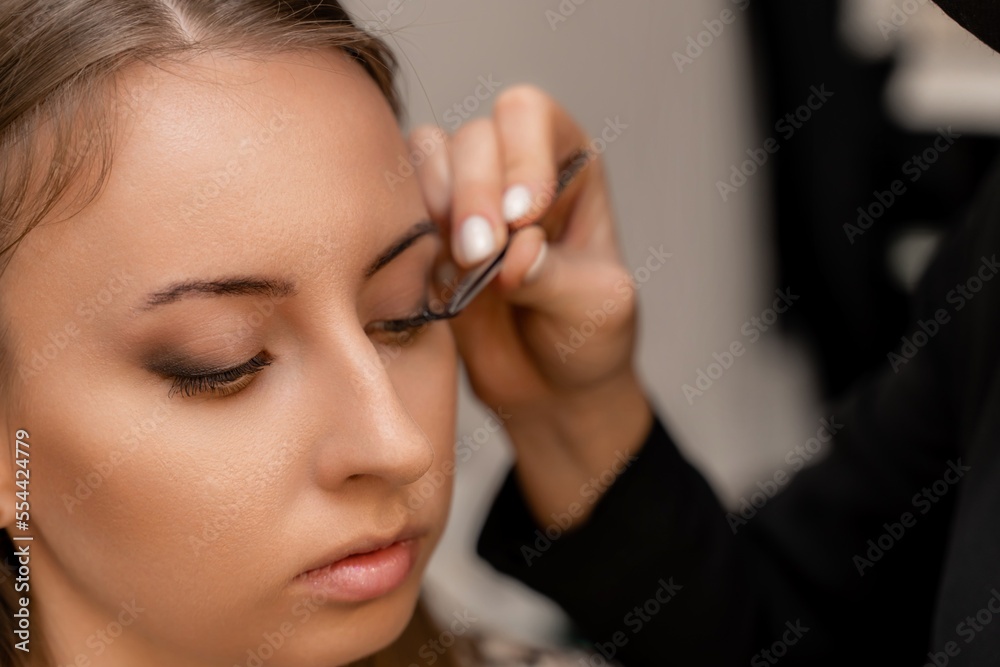 Makeup artist paints eyelashes to a woman in a beauty salon. Makeup artist paints eyelashes to a woman in a beauty salon.