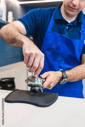 Professional barista who prepares a coffee latte in his small business.