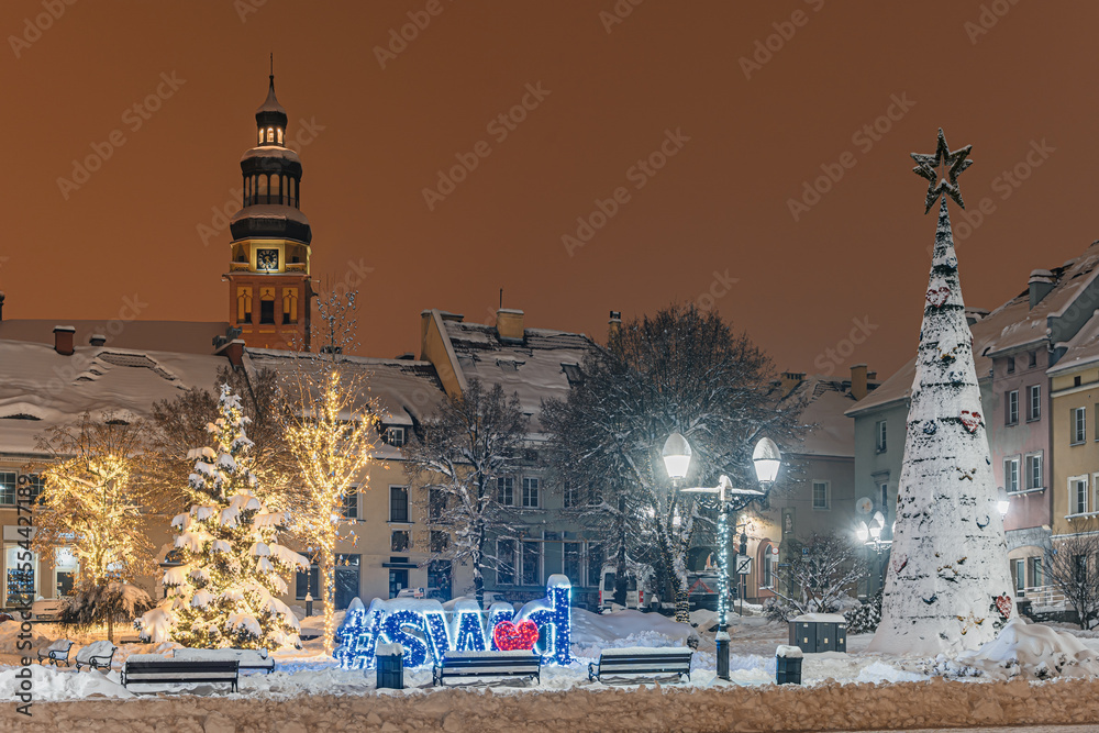 Rynek starego miasta zimą w nocy, Wodzisław Śląski w Polsce zasypany śniegiem z choinkami i światełkami świątecznymi
