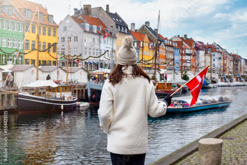 Canvas Print A tourist woman holding a Danish flag enjoys the view to the beautiful Nyhavn ar