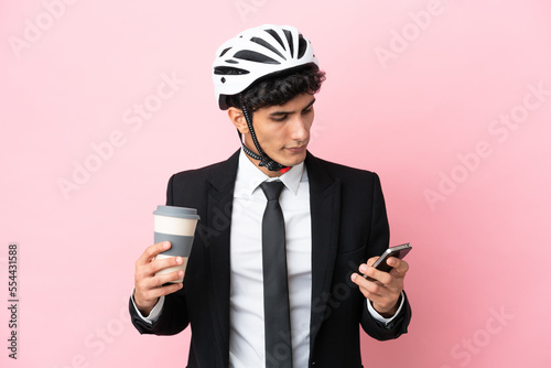 Argentinian businessman with bike helmen isoleted on pink background © luismolinero