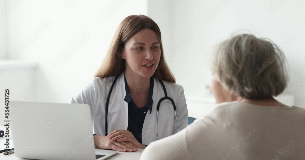 Young professional GP female doctor in white uniform talk to elderly woman patient, tell about treatment plan, explain prescriptions, medications at client visit in public clinic. Medicine, elderlcare Young professional GP female doctor in white uniform talk to elderly woman patient, tell about treatment plan, explain prescriptions, medications at client visit in public clinic. Medicine, elderlcare