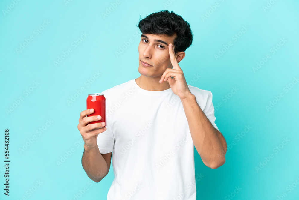 Young Argentinian man holding a refreshment isolated on blue background thinking an idea Young Argentinian man holding a refreshment isolated on blue background thinking an idea