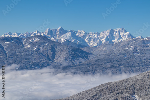 Scenic view of mountain summit Jof di Fuart (Vis) and Jof di Montasio in Julian Alps seen from Kobesnock near Bad Bleiberg, Carinthia, Austria, Europe. Heavy snow covered winter wonderland landscape