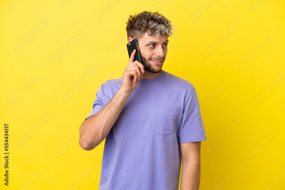 Young caucasian man using mobile phone isolated on yellow background looking to the side Young caucasian man using mobile phone isolated on yellow background looking to the side