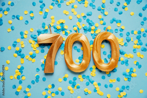 700 seven hundred followers subscriber card golden birthday candle on yellow and blue confetti Background. Template for social networks, blogs. celebration banner. 700 online community fans.