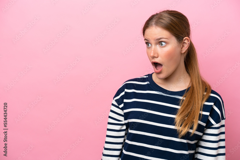 Young caucasian woman isolated on pink background doing surprise gesture while looking to the side Young caucasian woman isolated on pink background doing surprise gesture while looking to the side