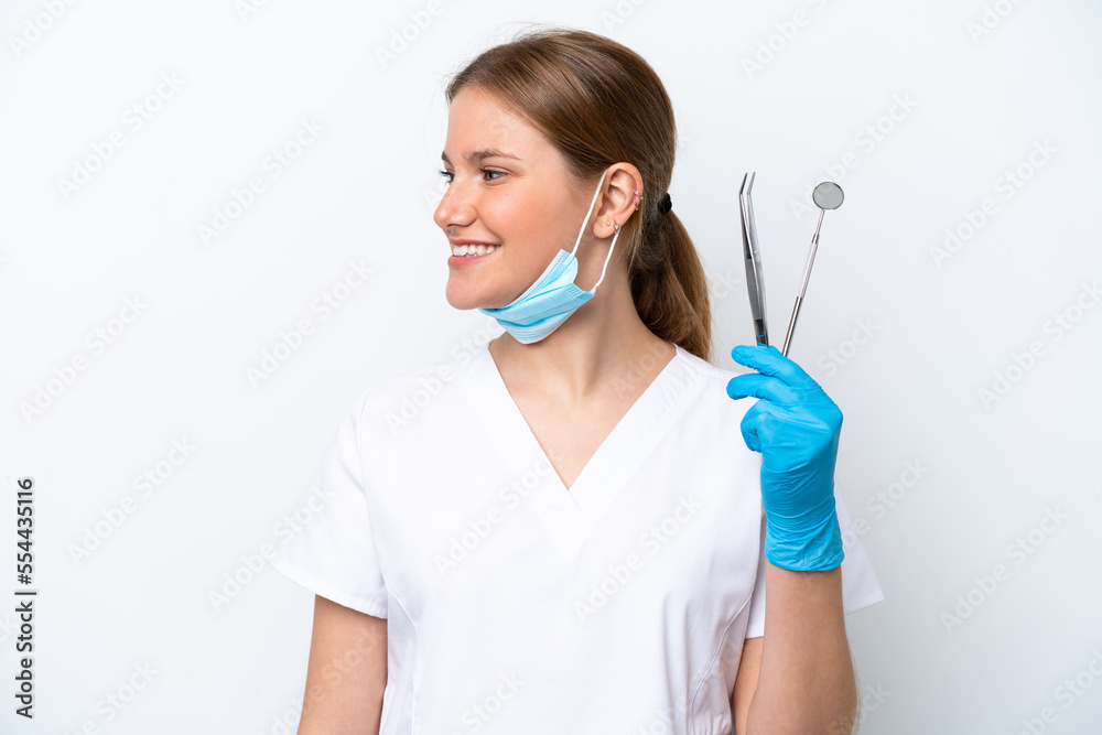 Dentist caucasian woman holding tools isolated on white background looking side Dentist caucasian woman holding tools isolated on white background looking side