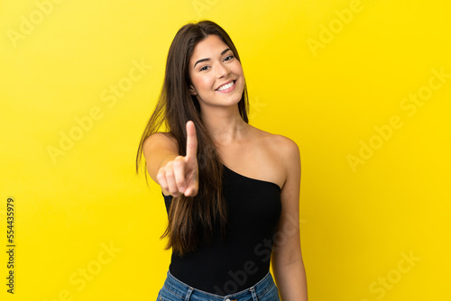 Young Brazilian woman isolated on yellow background showing and lifting a finger © luismolinero