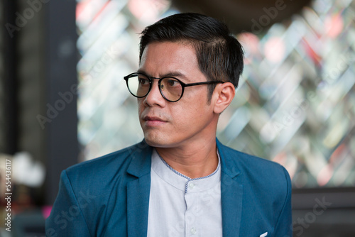 Close up of headshot Asian business man wear glasses and suit standing in the office