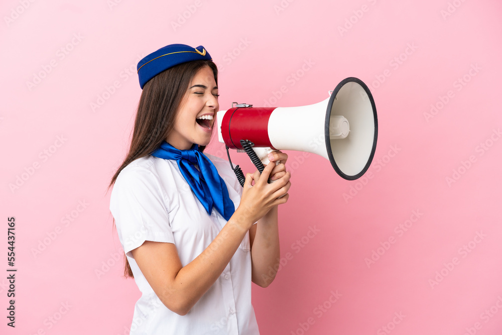 Airplane stewardess Brazilian woman isolated on pink background shouting through a megaphone Airplane stewardess Brazilian woman isolated on pink background shouting through a megaphone