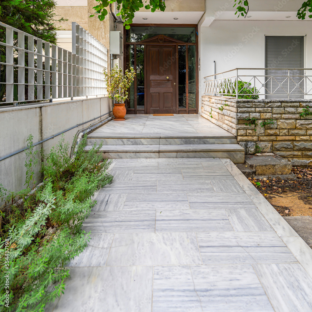 Fototapeta premium Exterior house entrance with marble floor and wooden door with classic design.