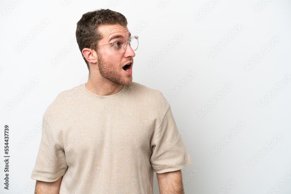 Young caucasian man isolated on white background doing surprise gesture while looking to the side Young caucasian man isolated on white background doing surprise gesture while looking to the side