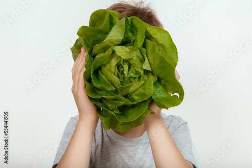Cheerful smiling young 6s boy wearing casual clothes posing holding green vegetable salad in hands looking at camera isolated on white wall color background studio portrait.