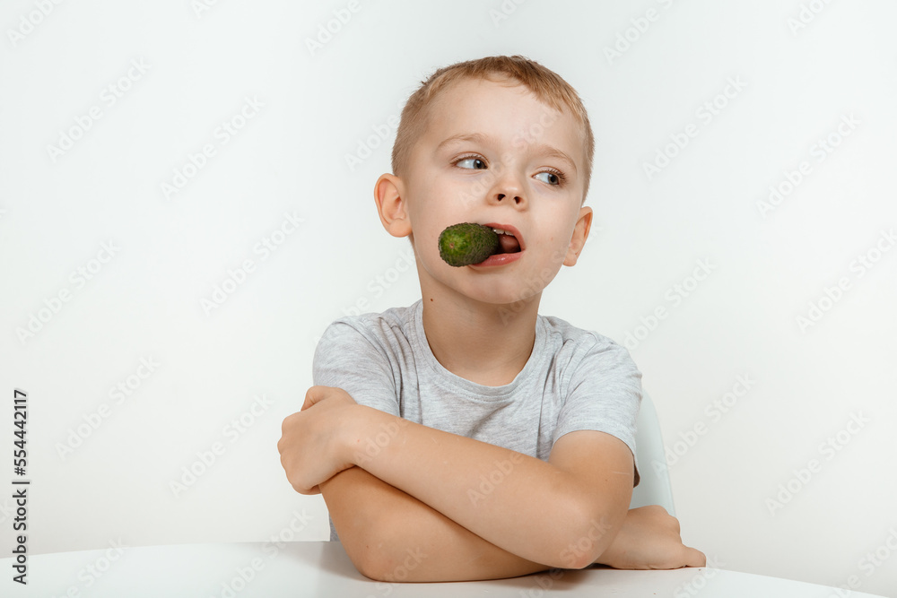 A little boy eats a fresh green cucumber. A little boy eats a fresh green cucumber.