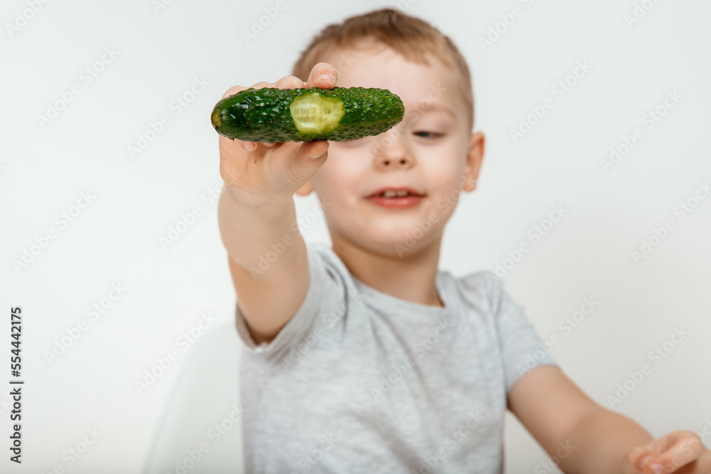A little boy eats a fresh green cucumber. A little boy eats a fresh green cucumber.